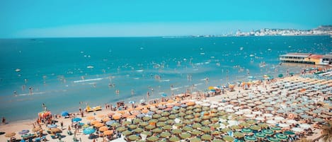 Nära stranden, vit sandstrand, parasoller och strandhanddukar