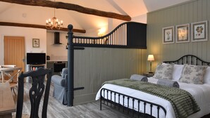 Quarto com cama, cadeira, televisão e lustre.
