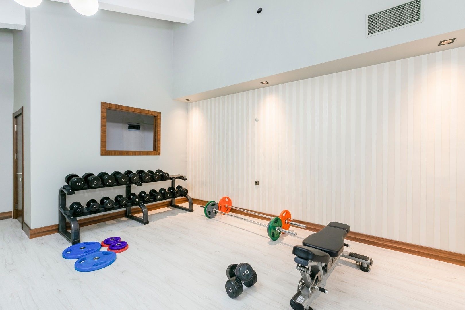 A gym with weightlifting equipment, including dumbbells, a bench, and weight plates.