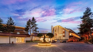 Un hôtel au design moderne, doté d’une cour intérieure avec une fontaine, entourée d’arbres et bordée d’un chemin pavé.