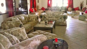 Una sala de estar con sofás estampados, una mesa de centro y cortinas rojas.