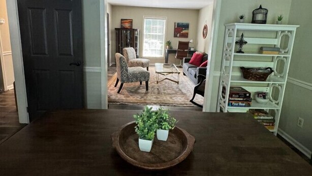 Un coin repas avec une table en bois foncé, deux plantes en pot et un ventilateur de plafond.