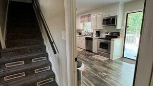 Un escalier mène à une cuisine moderne dotée d’appareils électroménagers intégrés et offrant une vue sur l’extérieur.