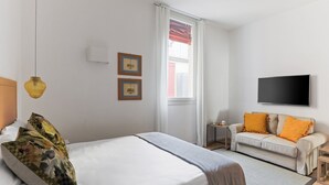 A hotel room with a bed, a sofa, a TV, and a window with curtains. - Le Porte, Luxury apartment UNIQUE TOWERS VIEW (Bologna)