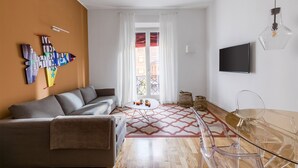A living room with a sofa, a coffee table, a TV, and a glass table. - Le Porte, Luxury apartment UNIQUE TOWERS VIEW (Bologna)
