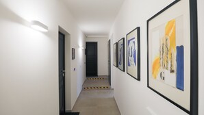 A hallway with framed artwork on the walls, a door at the end, and a light fixture on the left. - Le Porte, Luxury apartment UNIQUE TOWERS VIEW (Bologna)