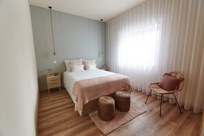 A bedroom with a bed, bedside tables, a chair, and a window with curtains.