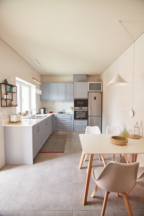 A modern kitchen with grey cabinets, a white island, and a dining area with a white table and chairs.