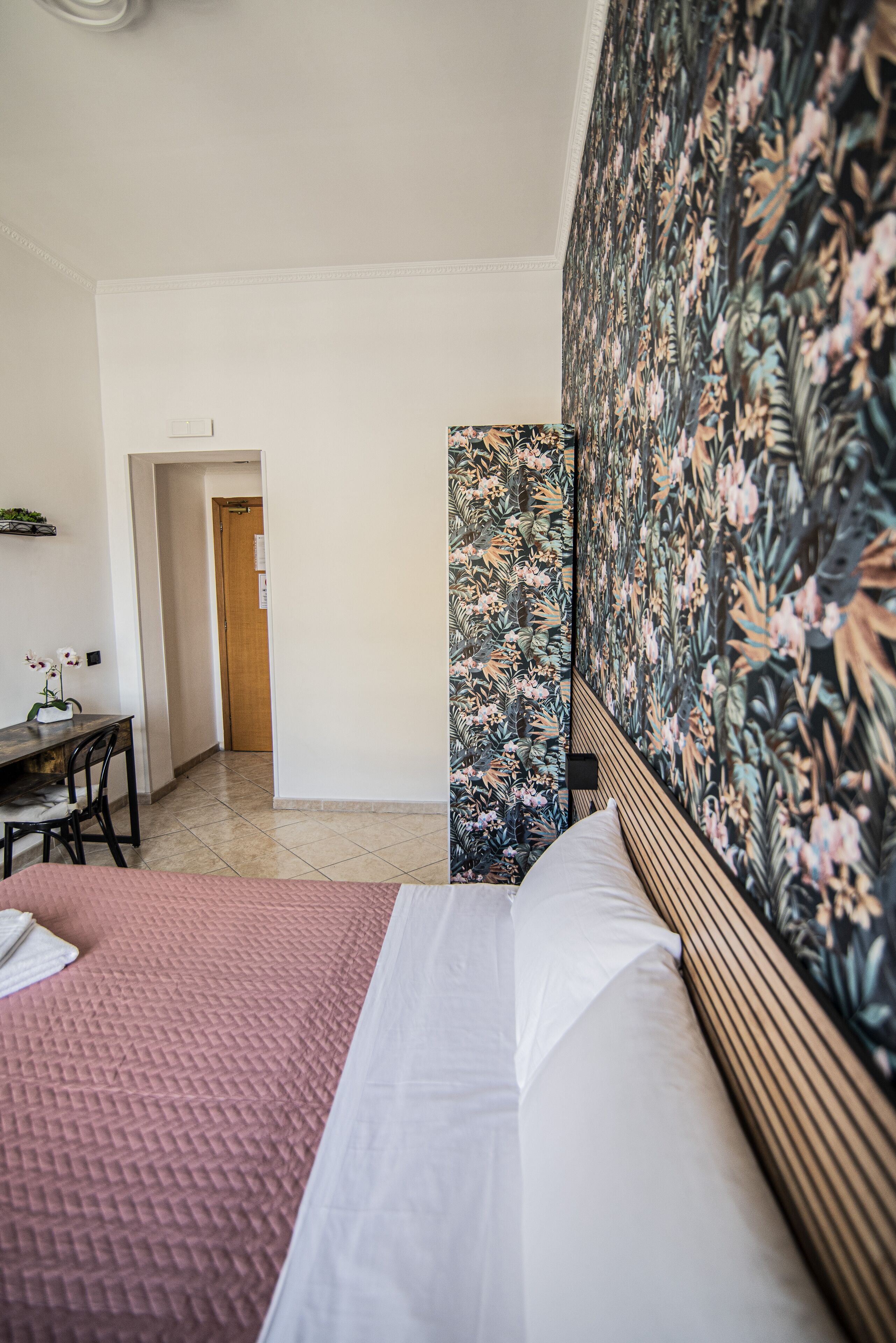 A hotel room with a bed, a desk, and a door leading to another room.