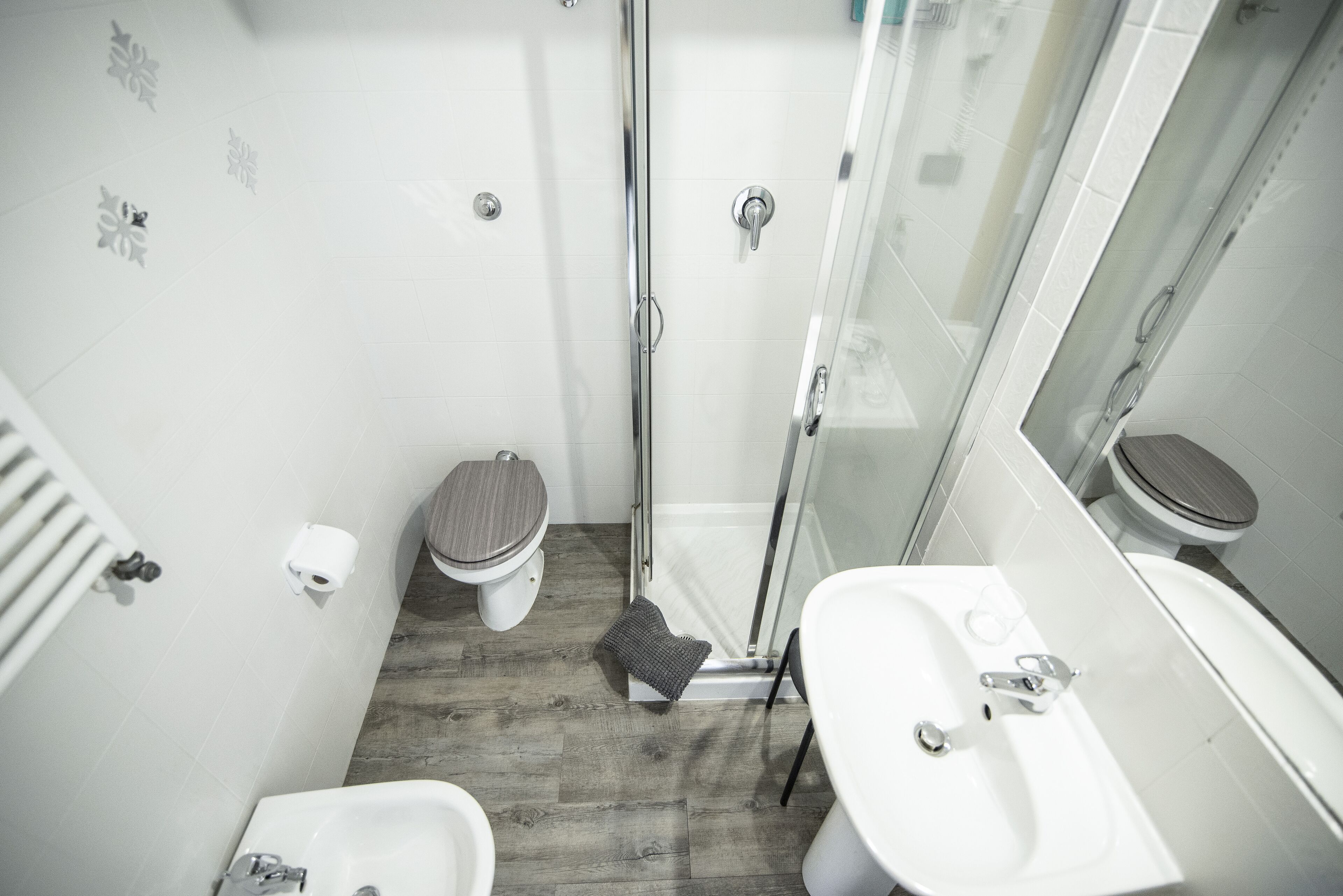 A compact bathroom with a shower, toilet, bidet, and sink.