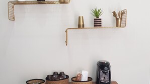 Una kitchenette con cafetera, tres cestas de mimbre y un cubo de basura.