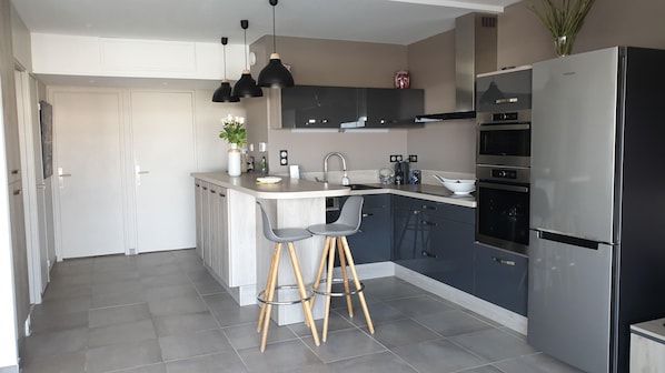 A modern kitchen with a built-in island, stainless steel appliances, and a minimalist design. - Port Camargue for rent MARINA type 3 (Le Grau-du-Roi)