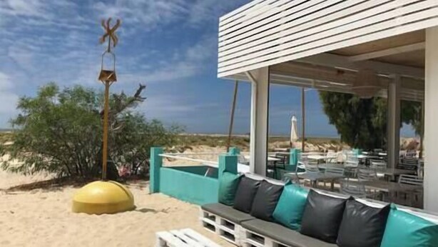 A beachside seating area with a white structure, a yellow exercise ball, and a view of the beach and ocean. - Casa W Olhão - ALMIRANTE (Olhão)