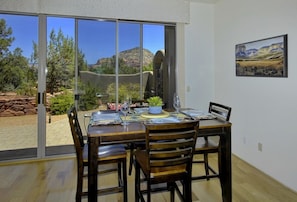 Enjoy meals with a view of the surrounding mountains from this dining area, which leads to a patio with a stone wall.
