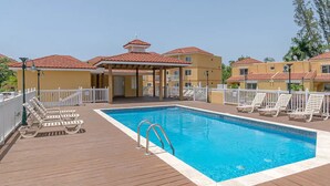 A swimming pool with lounge chairs and a covered area with a red roof. - Hospitality Expert CP (Montego Bay)