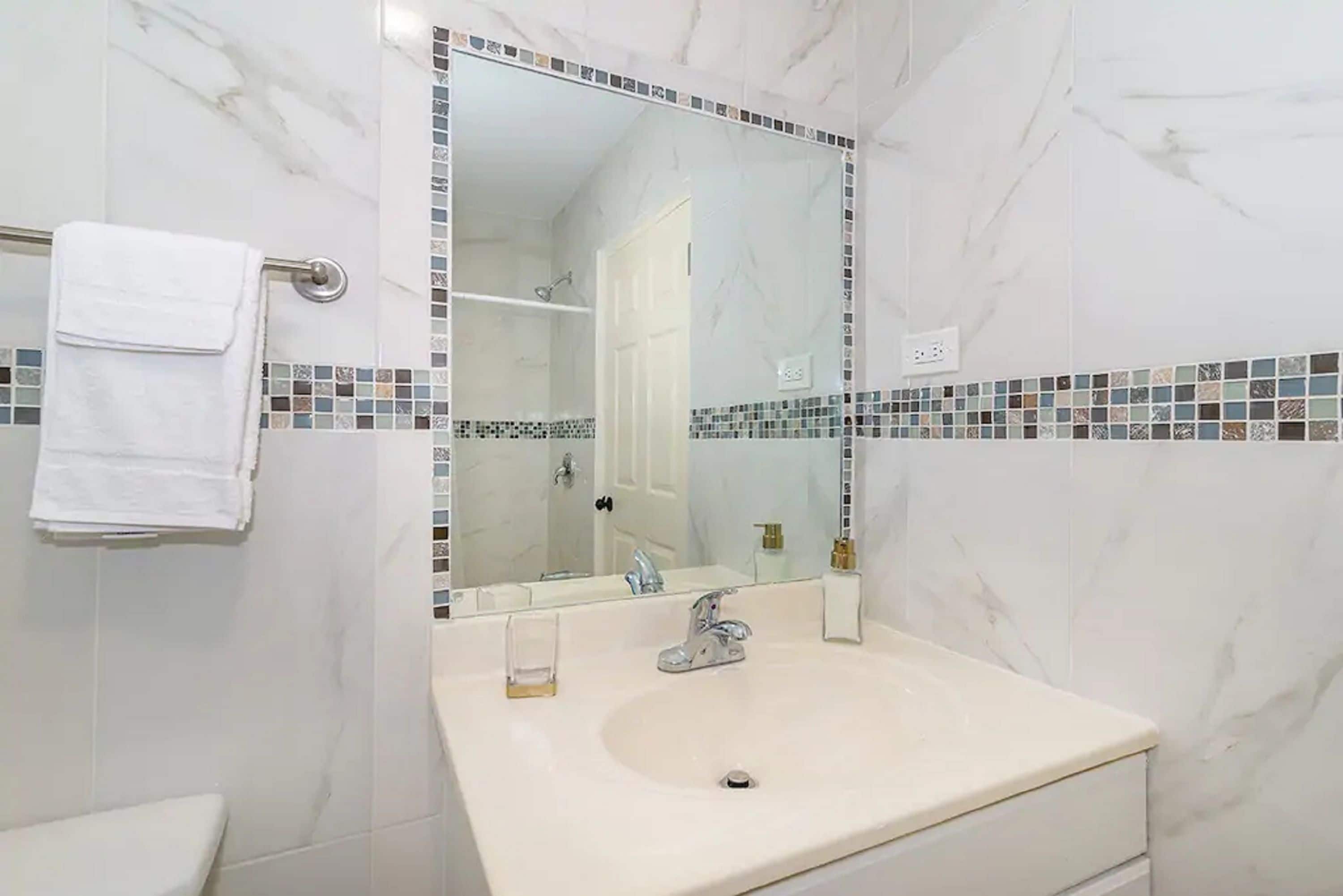 A bathroom with a white sink, a mirror, and a towel rack.