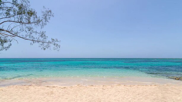 A beach with clear turquoise water and sandy shore. - Hospitality Expert CP (Montego Bay)