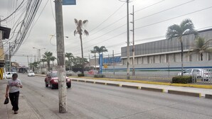 Escena callejera con coches, un peatón y un edificio con un cartel que dice "EL UNIVERSO".