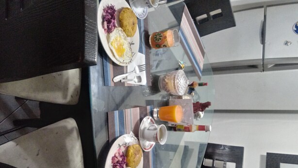 Una mesa de comedor con platos de comida, un vaso de jugo de naranja y una botella de agua.