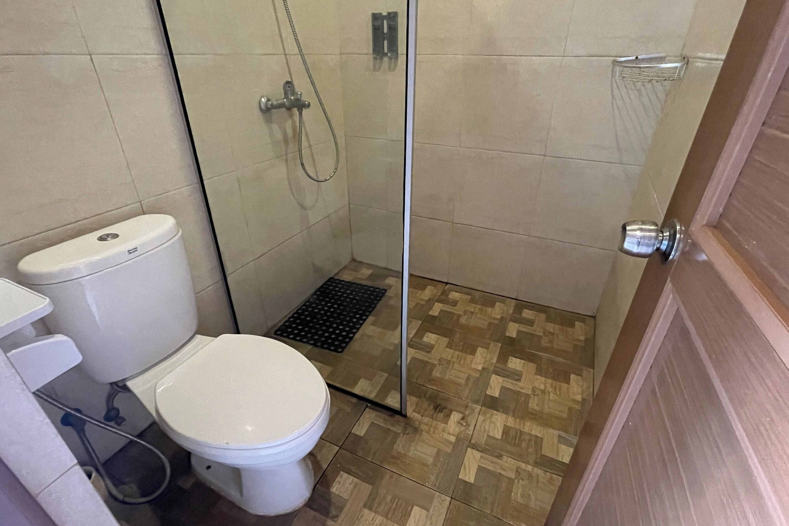 Une salle de bain avec des toilettes, une douche dotée d’une porte en verre et un plancher en bois.