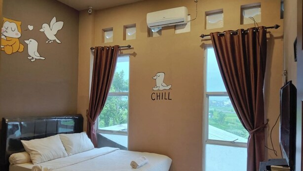 Ein Schlafzimmer mit einem Bett, einer Wand-Klimaanlage, einem Fenster mit Vorhängen und einer Wandsticker mit einem Hund und dem Wort "CHILL".