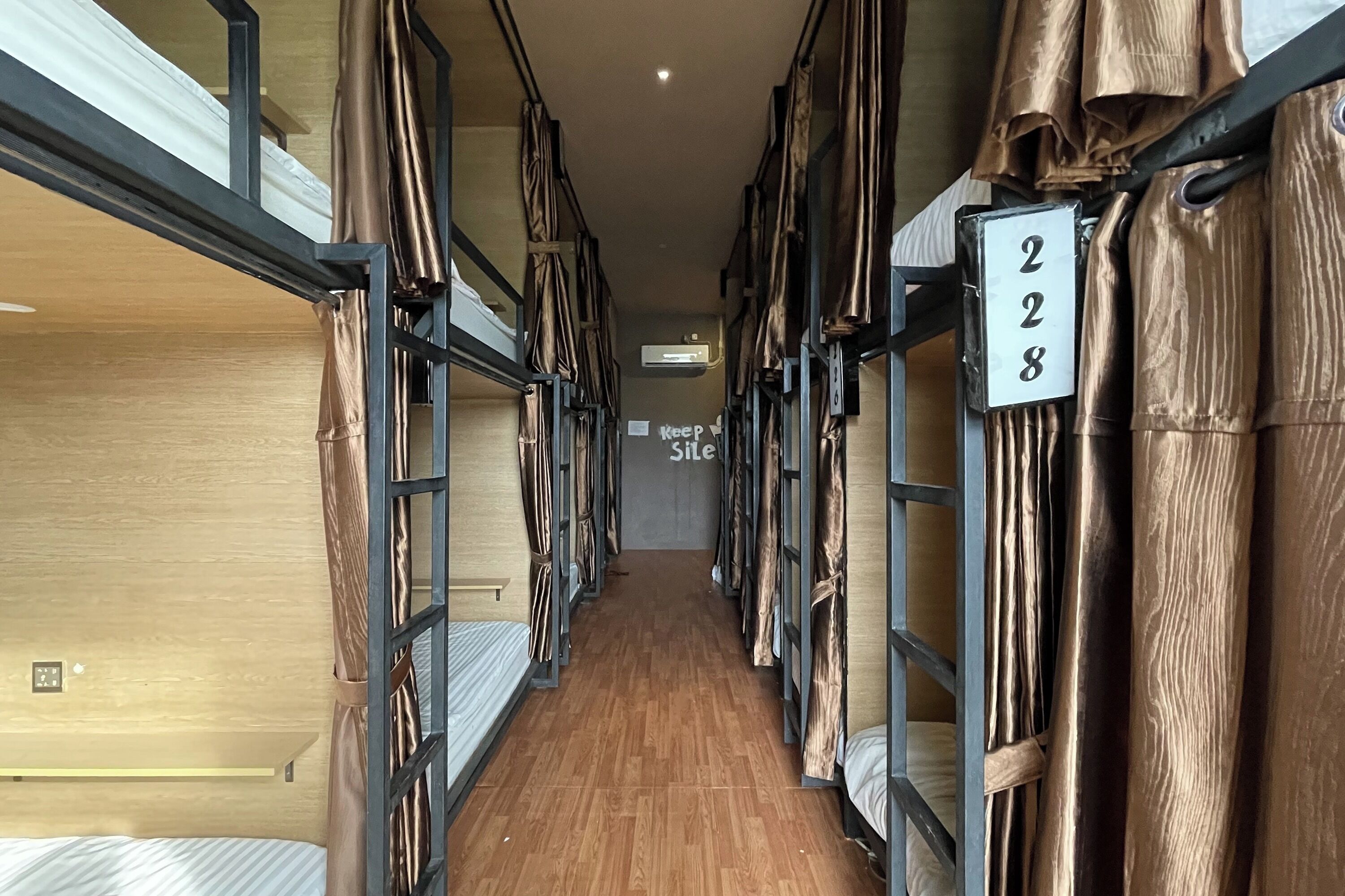 A corridor with bunk beds, numbered room signs, and a 'Keep Site' sign.