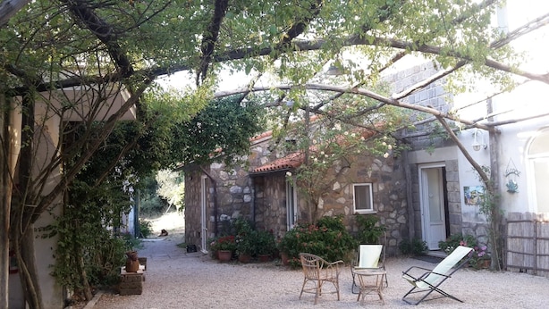 A stone building with a rustic charm, a gravel courtyard, and wicker furniture. - Azienda Agricola Le tore srl (Massa Lubrense)