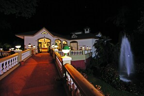 A hotel entrance with a paved walkway, a railing, and a fountain. - Usha Ascot (Karjat)