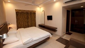 Une chambre d’hôtel équipée d’un lit, d’un ventilateur de plafond, d’un téléviseur à écran plat, d’un miroir et d’un appareil de climatisation.