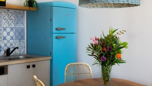 A kitchen with a blue refrigerator, a sink, and a dining table with chairs.