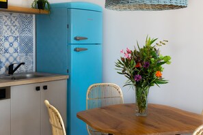 A kitchen with a blue refrigerator, a sink, and a dining table with chairs.
