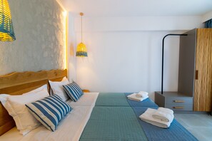 Ein ordentlich eingerichtetes Hotelzimmer mit Bett, Nachttischen, einem Kleiderschrank und einer Hängelampe.