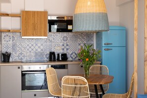 Eine moderne Küche mit einem blauen Kühlschrank, Korbstühlen und einem Esstisch.