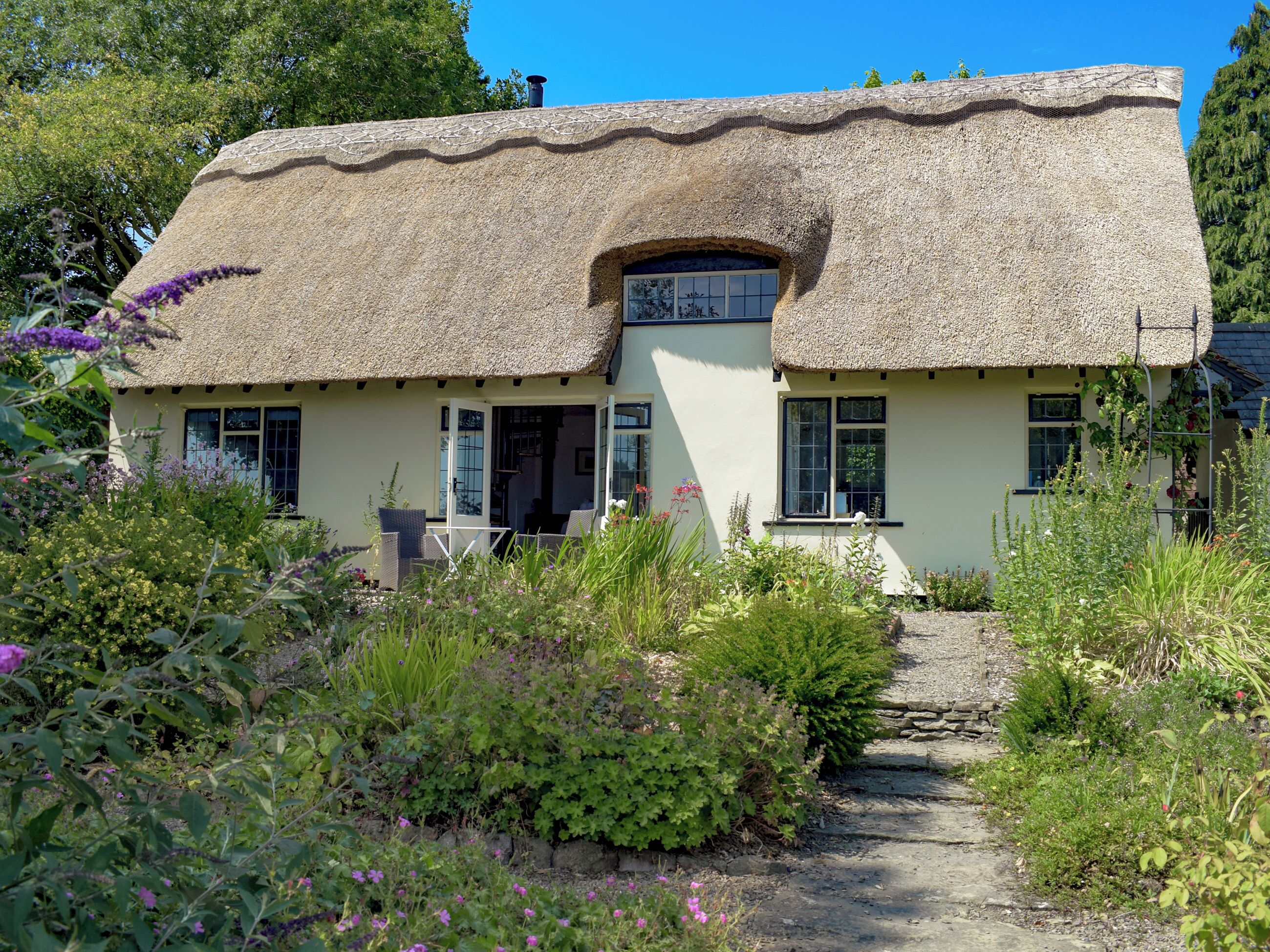 A thatched-roof cottage with a garden path leading to the entrance.
