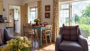 A dining area with a table set for four, wooden chairs, and a vase of flowers. - 2 bedroom accommodation in Richards Castle, near Ludlow (Richards Castle, near Ludlow)