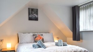 Quarto com cama, mesa de cabeceira e um quadro na parede.