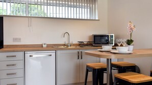 Cozinha moderna com lava-louças, micro-ondas, pia e área de refeições com banquetas.