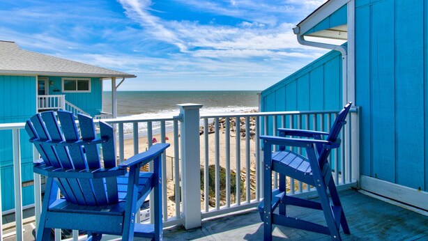 A balcony with two blue Adirondack chairs overlooking a beach. - ☀️Riggings K3-Beautiful Location and Views-Oceanfront Complex w/ Pool☀️ (Kure Beach)