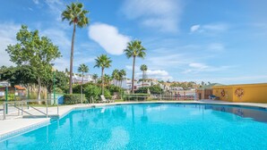 Una piscina azul cristalina rodeada de palmeras y un cielo despejado.