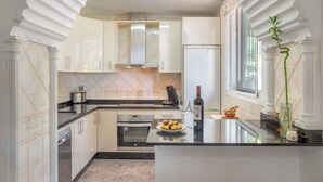 Una cocina moderna con armarios blancos, horno empotrado y un amplio ventanal que proporciona luz natural.