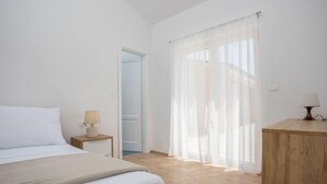 Un dormitorio con cama, mesita de noche, lámpara y cómoda de madera.