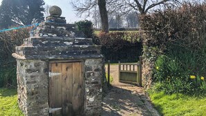 A stone structure with a wooden door, a stone pathway, and a wooden gate. - Well Farmhouse - UK11880 (Holsworthy, near Launceston)