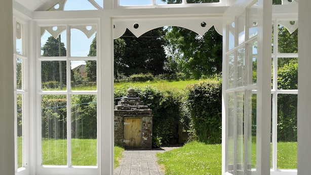 A conservatory with a stone pathway leading to a wooden door. - Well Farmhouse - UK11880 (Holsworthy, near Launceston)