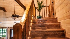 Una escalera de madera con barandilla, un ventilador de techo y una planta en maceta.