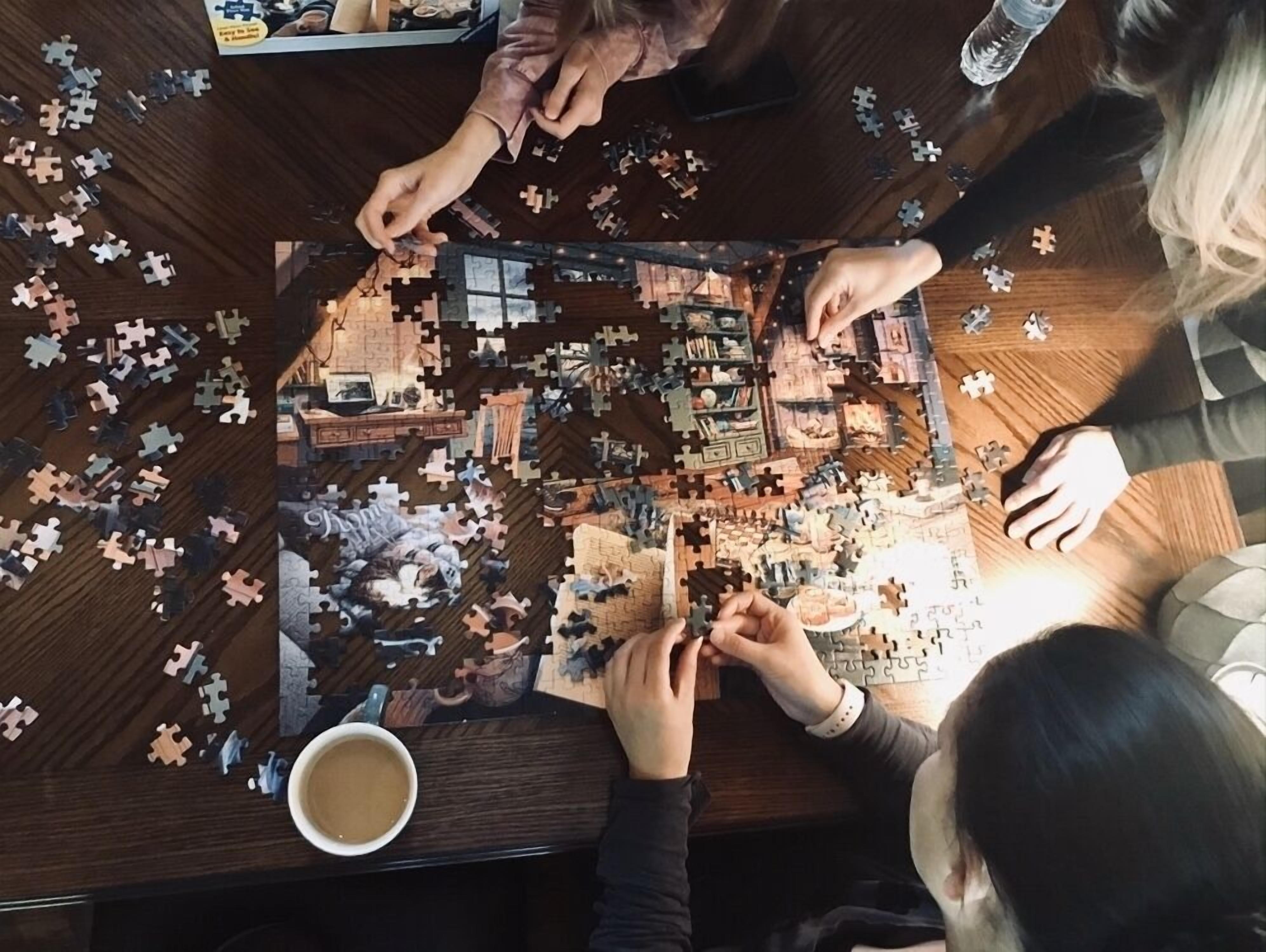 A group of people assembling a jigsaw puzzle on a wooden table.