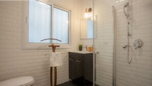 Un baño con inodoro, lavabo con espejo, toallero y ducha.