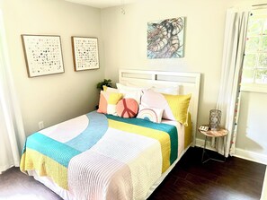 Cozy retreat with a neatly made bed, white headboard, and framed artworks.