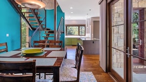 A modern interior with a dining area, staircase, and large sliding glass doors leading to an outdoor area. - Casita Grove-2 Lakeside Homes w/Casita & Boat Lift (Burnet)
