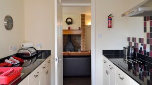 A modern kitchen with a black countertop, white cabinets, a brick fireplace, and a clock on the wall.