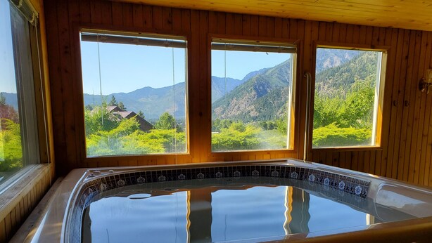 A wooden cabin with a hot tub and large windows offering a mountain view. - Ski Hill home w/ stunning views & hot tub! (Leavenworth)